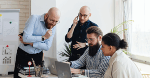 group of people surrounding a laptop working and learning